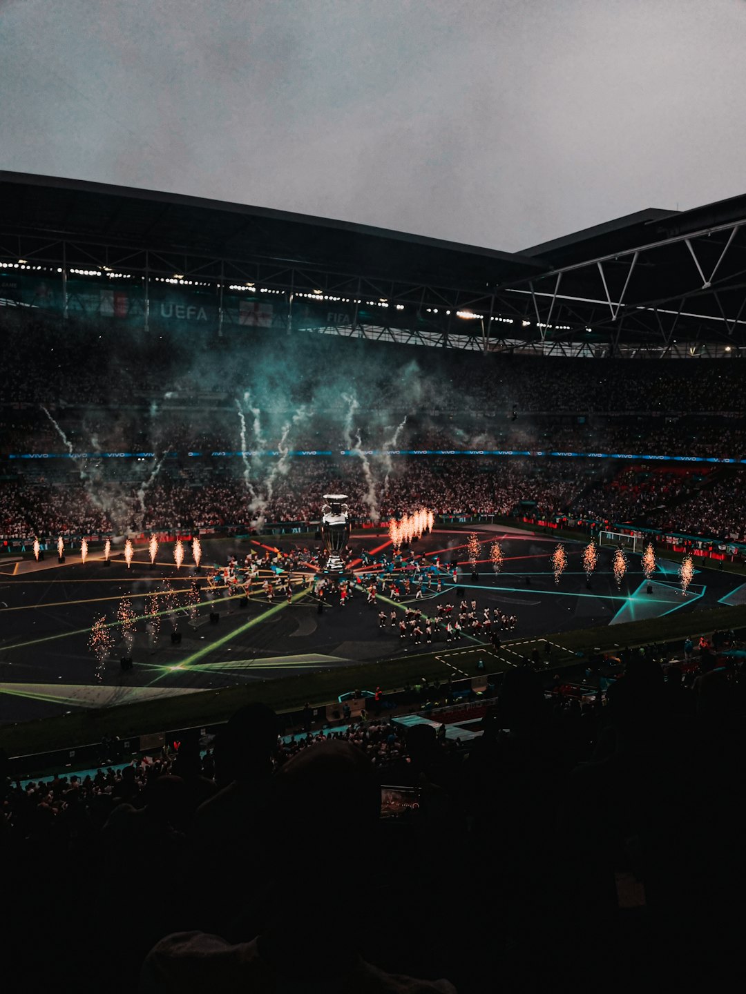 A golden trophy sits on a football field during a stadium celebration.