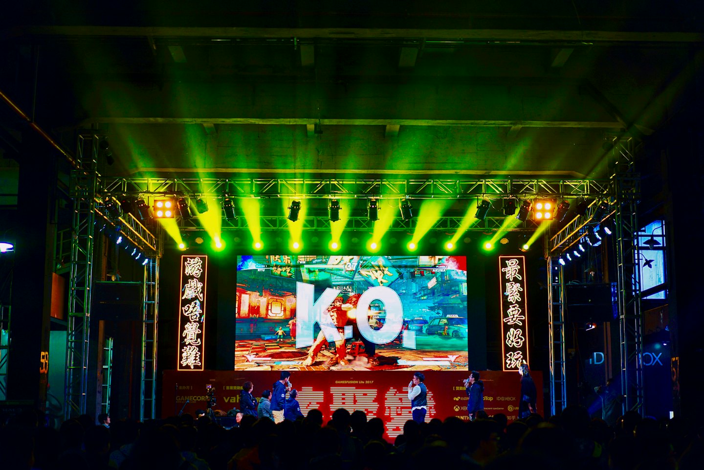 Esports competition with 'K.O.' on a large screen.